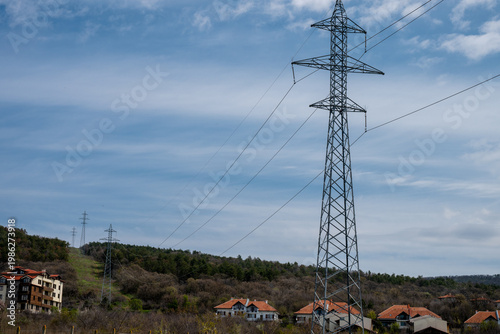 Billede på lærred a high-voltage transmission pylon towering over a residential neighborhood and f