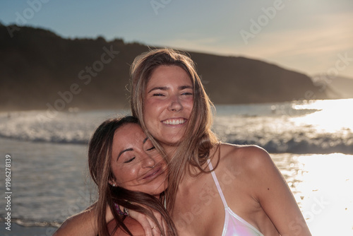 Happy young women embracing on beach during sunset