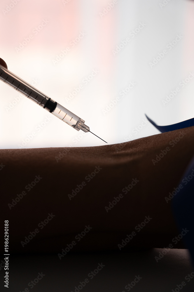 Naklejka premium Syringe preparing injection on arm with tourniquet
