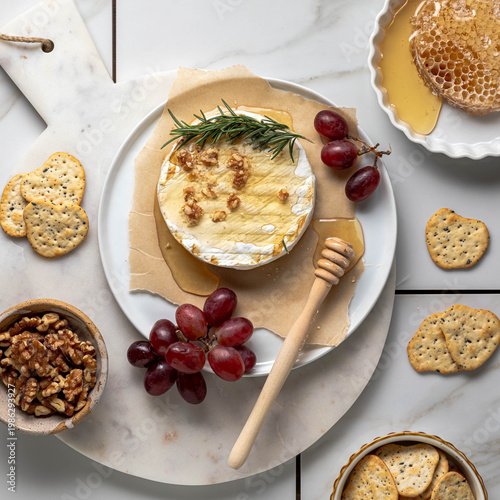Above view of an arrangement of brie with honey served with grapes and crackers.