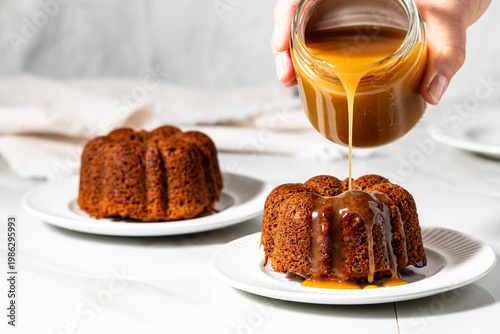Mini sticky toffee pudding bundt cakes with caramel sauce being poured on top.