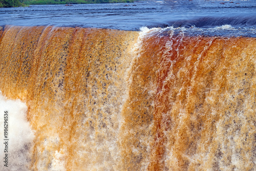 Brown Water Rusing Over the Brink of a Waterfall