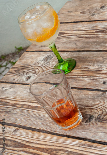 фотографія Glasses of  light brown soda and gin tonic with ice cubes and orange peel diagon