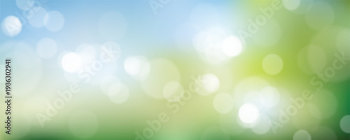 Abstract nature bokeh background featuring soft blue sky and vibrant green foliage.