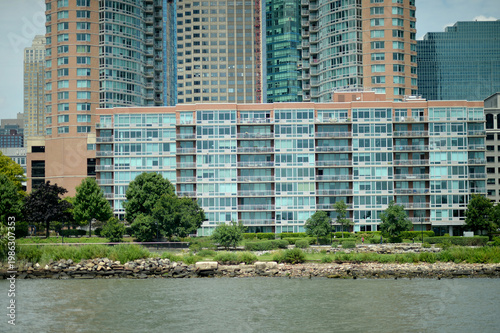 Riverfront Apartment Scene. Contemporary Dwelling Featuring Green Lawns And Cityscape Backdrop