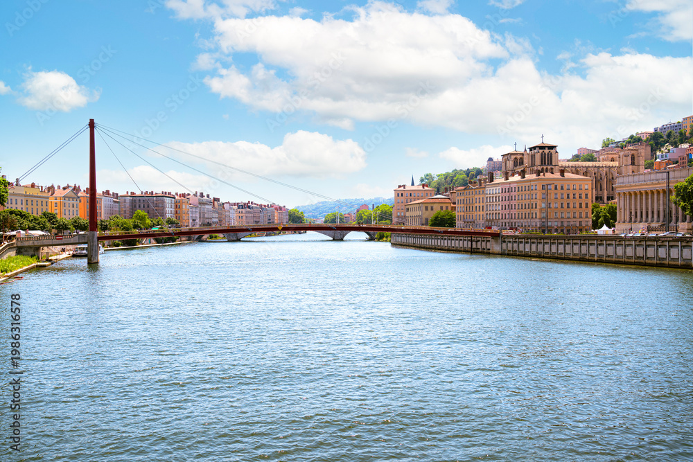 Obraz premium The Saône River in Lyon, red mast of the Passerelle du Palais de Justice on the left. The skyline of Vieux Lyon dominates the right bank, with the columns of the Palais de Justice