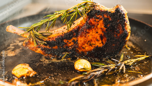 Canvas Print Pork cutlet searing in a pan with garlic and rosemary, steam rising