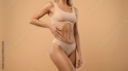 A clean studio shot of a young blonde tanned woman in minimal inner wear