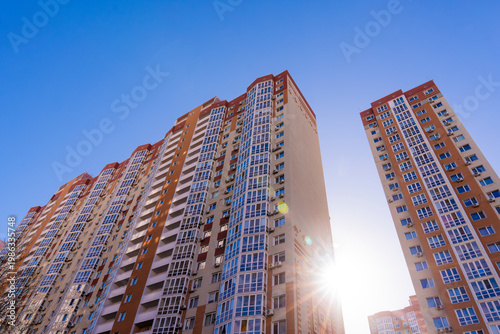 Exterior view of high-rise apartment buildings with colorful facades under a bright blue sky in a modern city district