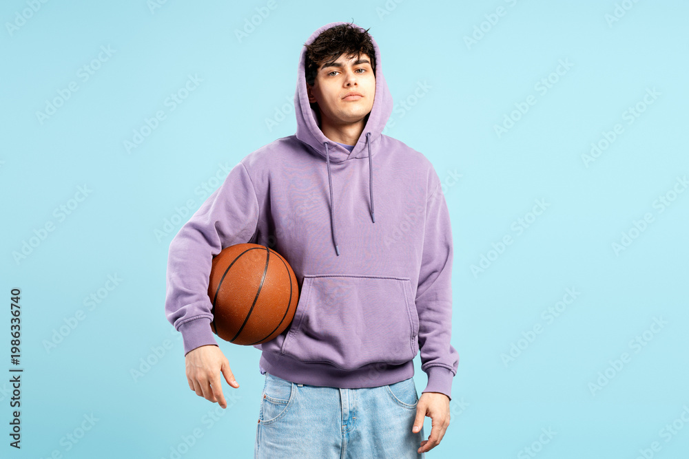 Naklejka premium Teenager holding basketball wearing purple hoodie