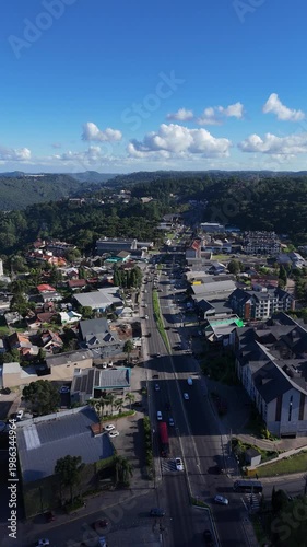 Vista vertical aérea da cidade de Gramado no Rio Grande do Sul com arquitetura europeia, ruas movimentadas e turismo intenso destacando o charme urbano da serra gaúcha
