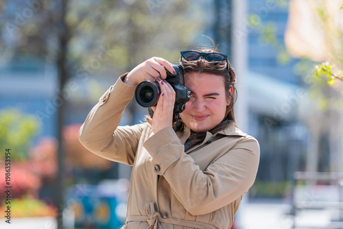 Young woman takes pictures with camera on sunny day in the city