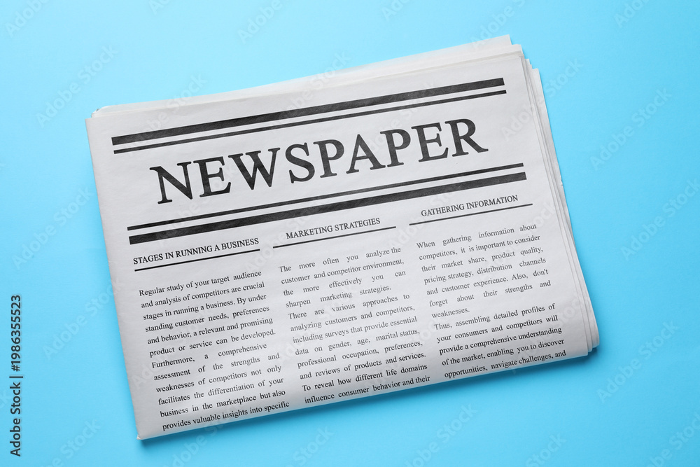 Fototapeta premium Folded newspaper on light blue background, top view
