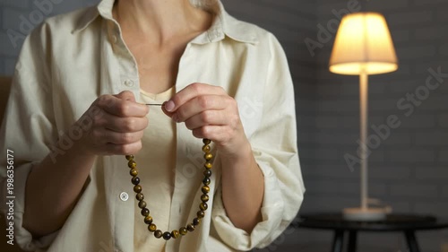Woman's hands with tiger's eye beads. Woman fingering tiger's eye beads on a string
