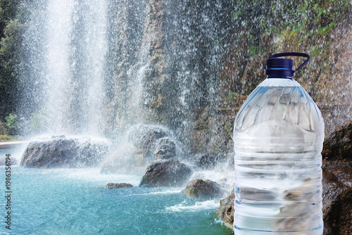 Pure water. Bottle against beautiful view on waterfall