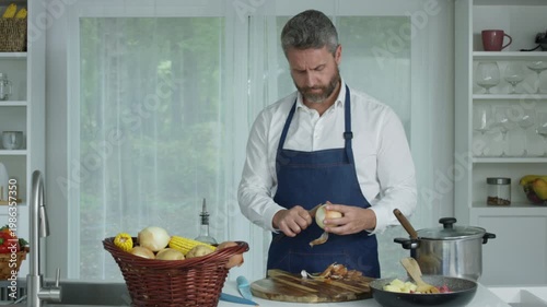 Middle aged Man cooking fresh vegetables in kitchen. Cooking delicious dish with love. Male chef cooking healthy food for lunch. Home cooking.