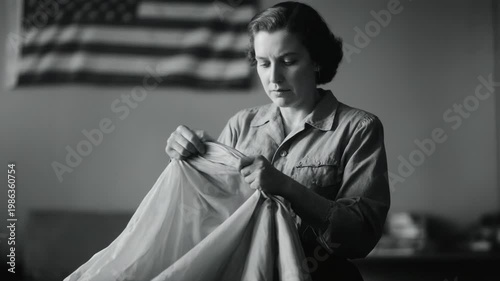 Woman worker inspecting parachute fabric in a workshop. World War II home front labor. Vintage black and white footage of female factory worker