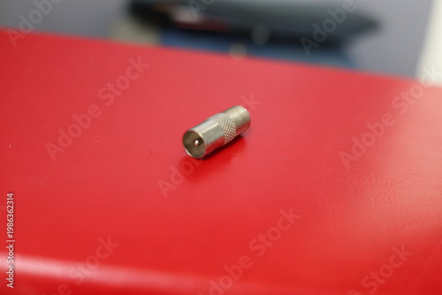 Close-up of a silver coaxial cable connector lying on a textured surface