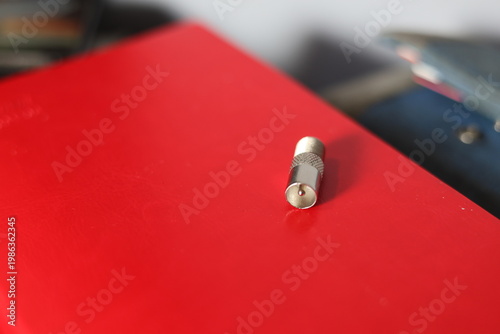 Close-up of a silver coaxial cable connector lying on a textured surface