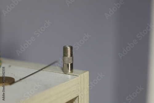 Close-up of a silver coaxial cable connector lying on a textured surface