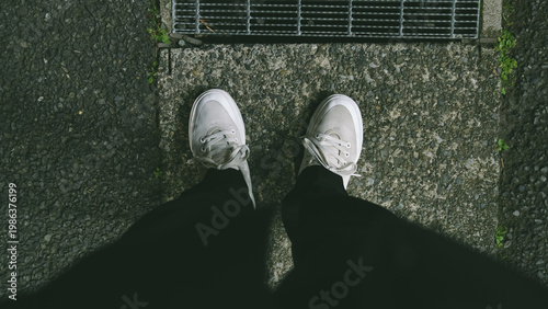 アスファルトの上に立つ白いスニーカーと街角の風景 / White sneakers on asphalt, urban lifestyle top view