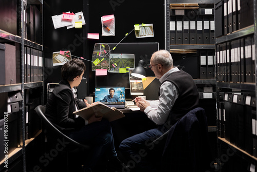 Tablou pe pânză Detectives hold a teleconference with the chief in an incident room, reviewing criminal records and organizing evidence records