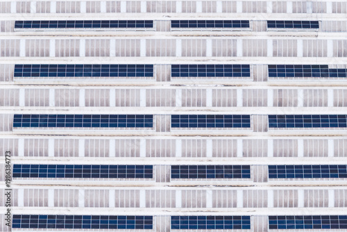 Aerial view of rows of solar panels installed on a large industrial warehouse roof with a geometric pattern Leccio, Toscana, Italy.