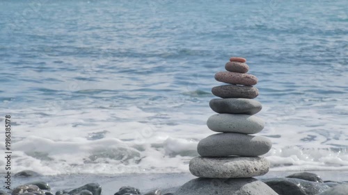 beach with cairn rocks, zen-like pebbles stacked in balanced pyramid against ocean waves, Balanced stones on beach, Meditation and mindfulness, harmony, travel, and serenity coastal retreats