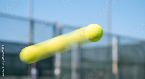 Close-up of a fast მოძრving tennis ball with strong motion blur on outdoor court, illustrating speed, precision, and dynamic sports action.