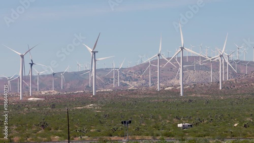 Footage of large white wind turbines generating renewable energy in a wind farm from ground level.