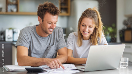 Happy young couple managing finances and budgeting together at home with a laptop