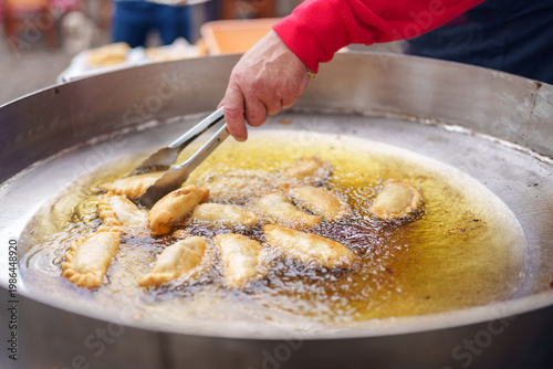 Person deep frying empanadas in hot oil