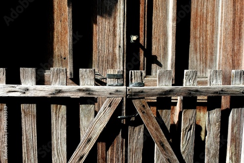 Fotografie The an old wooden fence with a worn color and distinctive texture in front of the main entrance of a house in the countryside