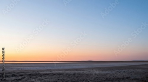 Vast flat landscape at dusk with subtle orange horizon and clear blue sky