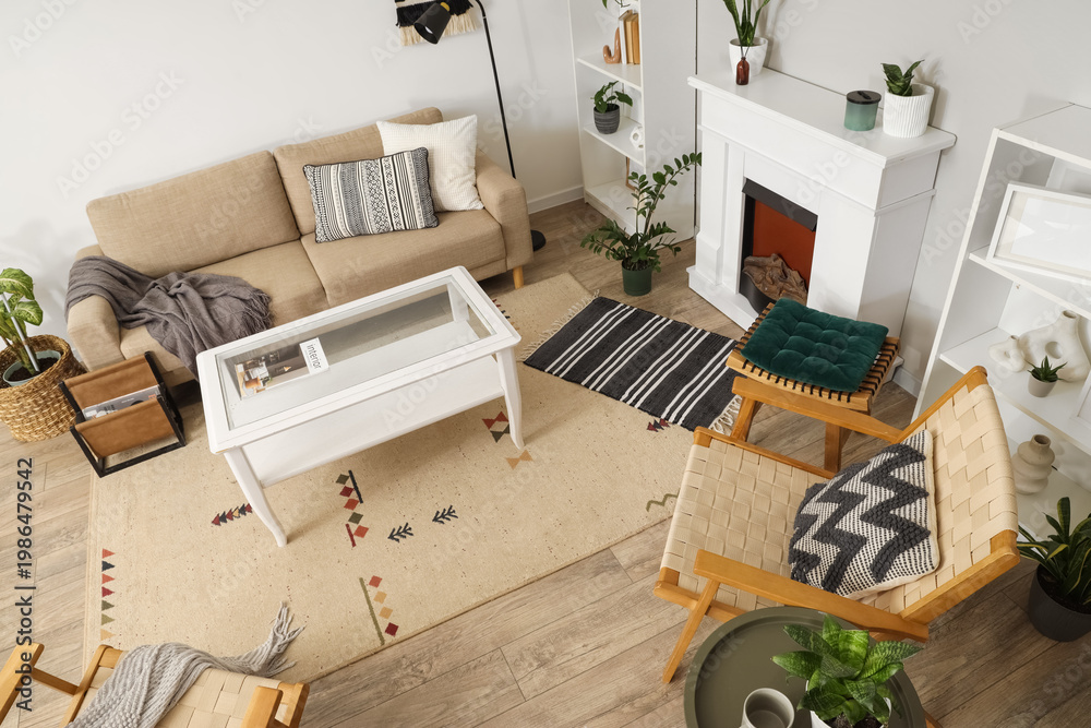 Fototapeta premium Interior of light living room with green plants, sofa and fireplace, top view