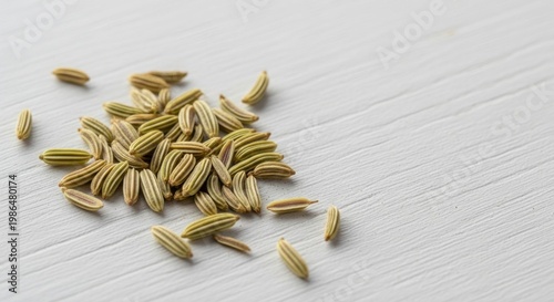 Tiny fennel seeds lying on a plain white textured background