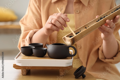 Young woman putting dry tea...