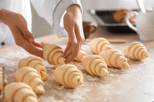 Bild auf Leinwand Female baker making croissants at table in kitchen