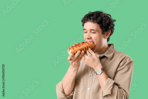 Young man eating tasty hot ...
