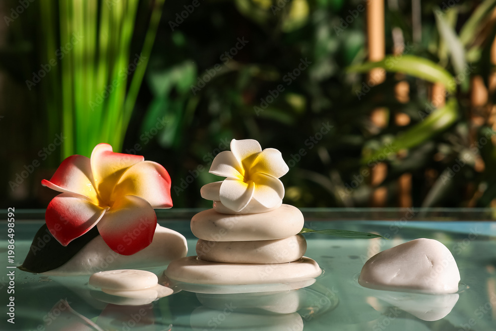 Naklejka premium Lake with spa stones and beautiful plumeria flowers in tropical bamboo garden