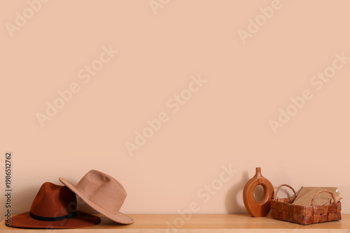 Foto Stylish hats with books and vase on shelf near beige wall