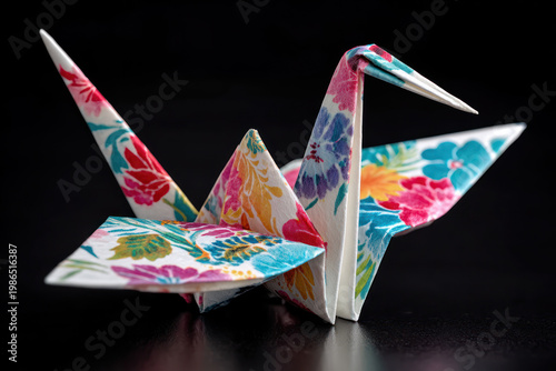 Origami crane floral pattern paper bird colorful folded craft hope symbol on black background evoking calm promise of future blooming.