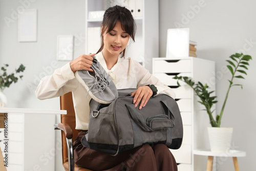 Young businesswoman with sports bag and sneakers sitting in office