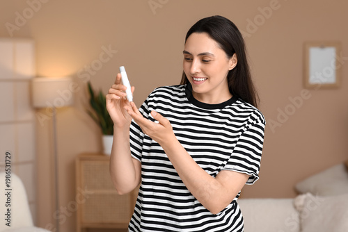 Diabetic young woman using lancet pen at home