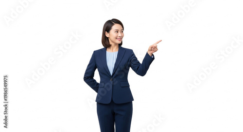 Confident young Asian businesswoman in a navy suit pointing to the side, indicating a concept or presenting an idea with a friendly smile on a clean white background