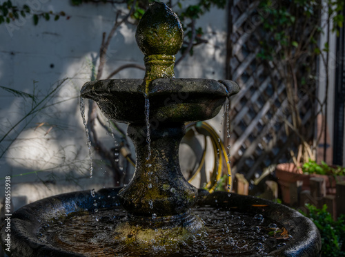 Slika na platnu Weathered stone tiered garden fountain with moss and flowing water in a quiet co