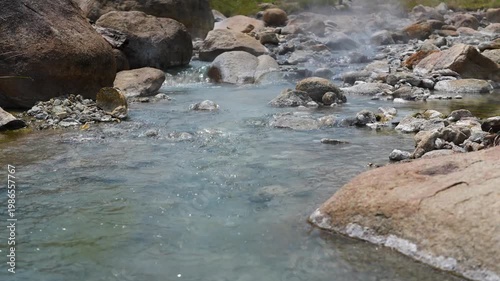 Hot mineral water with steam flowing through stones and rocks at Pai city hot springs in Northern Thailand, popular tourist sightseeing spot, natural hot geothermal water pools retreat in Asia.