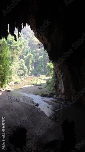 Entrance in exotic cave surrounded by tropical forest, flowing stream and thousands of bats flying inside. Thum Lod Cave in national park of Northern Thailand, popular sightseeing landmark for tourist