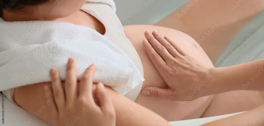 Fototapeta premium Young pregnant woman with doula lying in bathtub at home