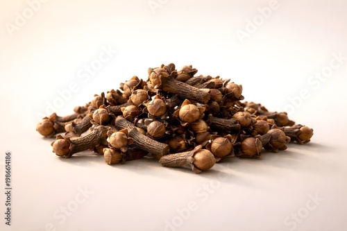 Premium dried clove spice pile isolated on soft neutral background, natural texture, warm light, minimal composition